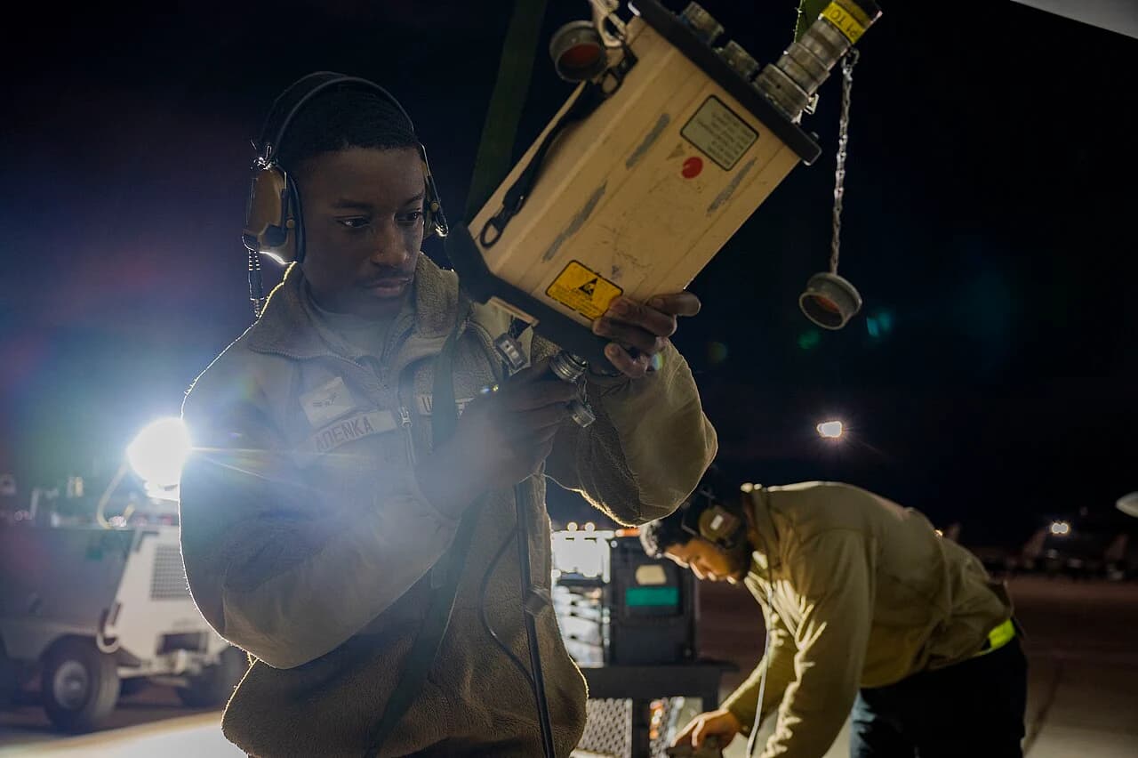 Avionics technician working beside an open aircraft electronics bay