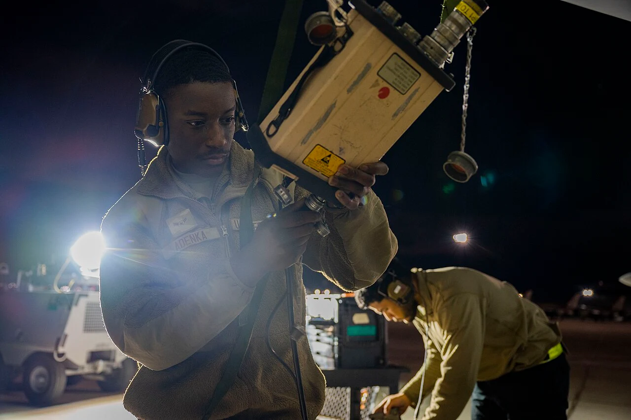 Avionics technician working beside an open aircraft electronics bay
