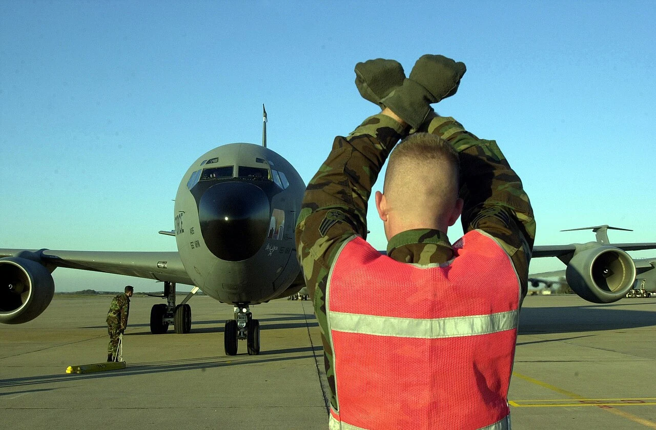 Ground crew marshaller signalling to an aircraft on the apron
